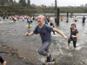 Ellie Vanschoiack, 12, of Vancouver, runs out of Klineline Pond after taking in a dip Thursday during the Polar Plunge at the Clark County 16th Annual Turkey Trot. More than 1,200 participants walked or ran and more than 100 swam during the Thanksgiving event. Top: Chase Lund, left, and his dad, Eric, try to push each other into the cold water of Klineline Pond.