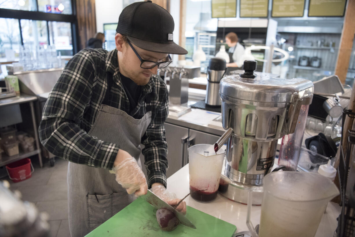 Michael Miller cuts a beet to insert into a juicer while making fresh juice Tuesday at Mighty Bowl in downtown Vancouver, recently selected as the most hip city in America by MoveHub. Though juice bars may not be a factor in how hip a city is ranked, the prevalence of vegetarian food did impact a city’s score.