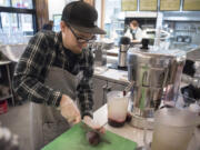 Michael Miller cuts a beet to insert into a juicer while making fresh juice Tuesday at Mighty Bowl in downtown Vancouver, recently selected as the most hip city in America by MoveHub. Though juice bars may not be a factor in how hip a city is ranked, the prevalence of vegetarian food did impact a city’s score.