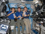 Astronaut Koichi Wakata, from left, Expedition 19 commander Gennady Padalka and astronaut Mike Barratt of Camas share a toast on May 20, 2009, to celebrate the space station’s new recycling system that converts urine, sweat and atmospheric humidity back into drinking water.