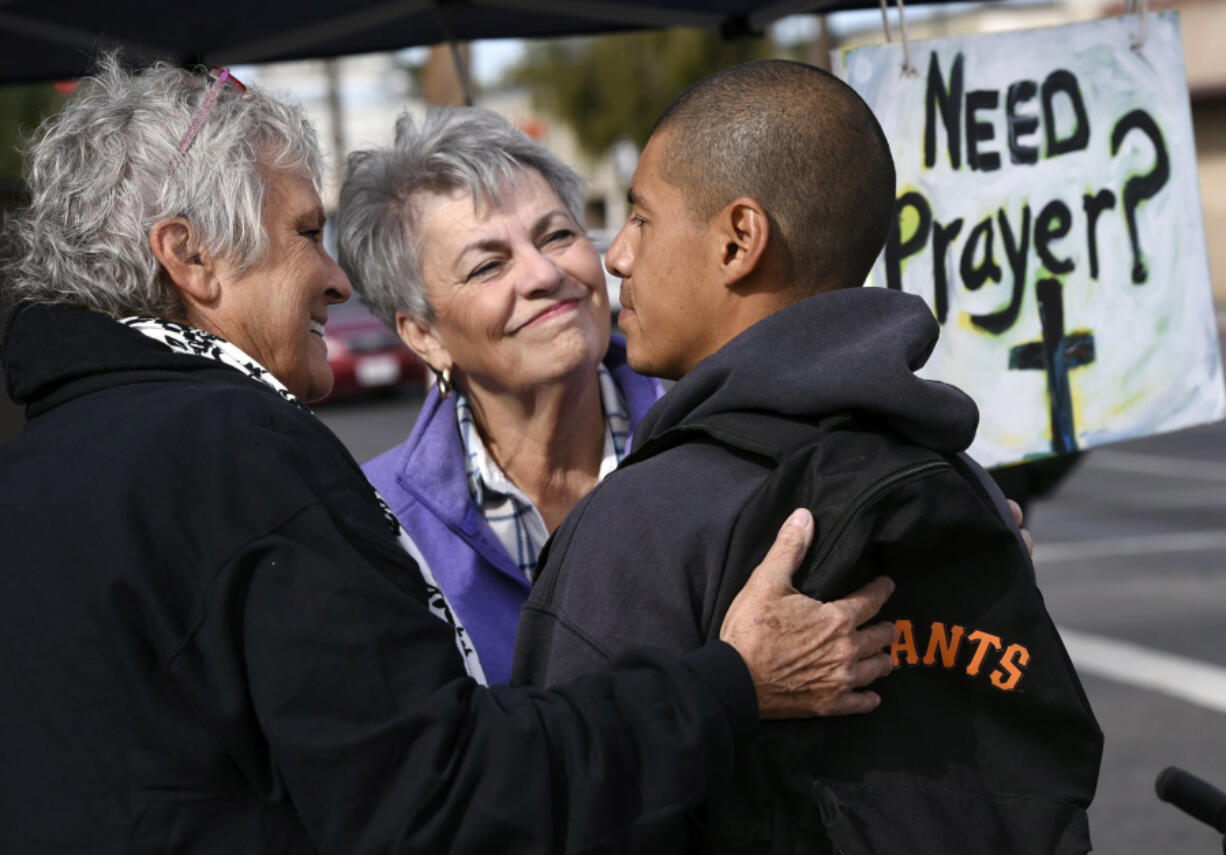 Ivan Mendoza, who was riding his bike when he stopped for a prayer, listens as Virginia La Salle, left, and Linda Crowder, center, chat with him at a pair of canopies set up for free prayers on Oct. 20.