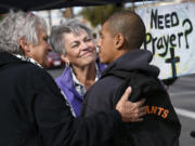 Ivan Mendoza, who was riding his bike when he stopped for a prayer, listens as Virginia La Salle, left, and Linda Crowder, center, chat with him at a pair of canopies set up for free prayers on Oct. 20.