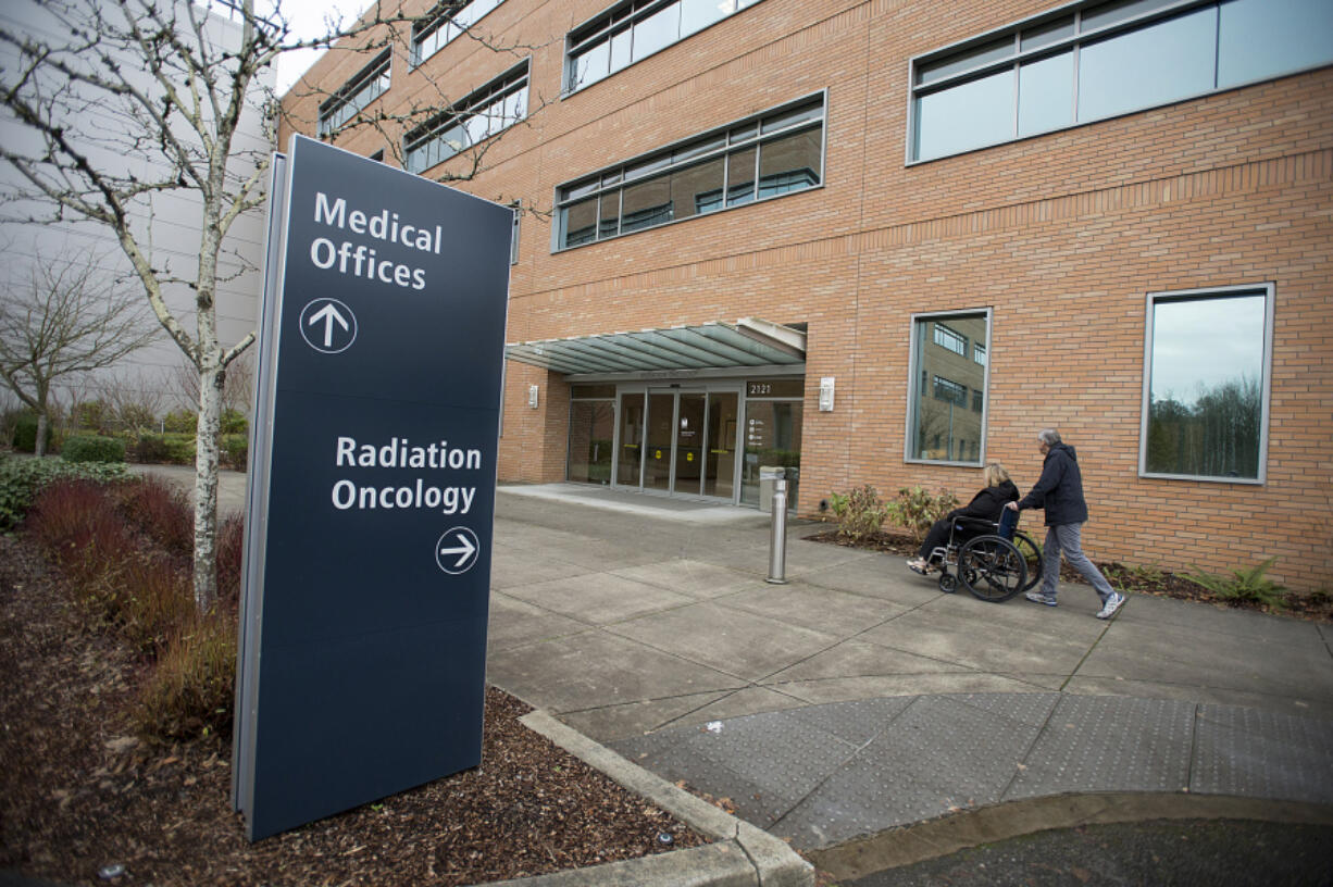 John Cummings assists client Linda Stithem as he drops her off for an appointment at Legacy Salmon Creek Medical Center in December.