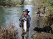 The author holds a coho as his “quality assurance officer,” right, checks it out. November is a great time in local river for late runs of coho salmon.