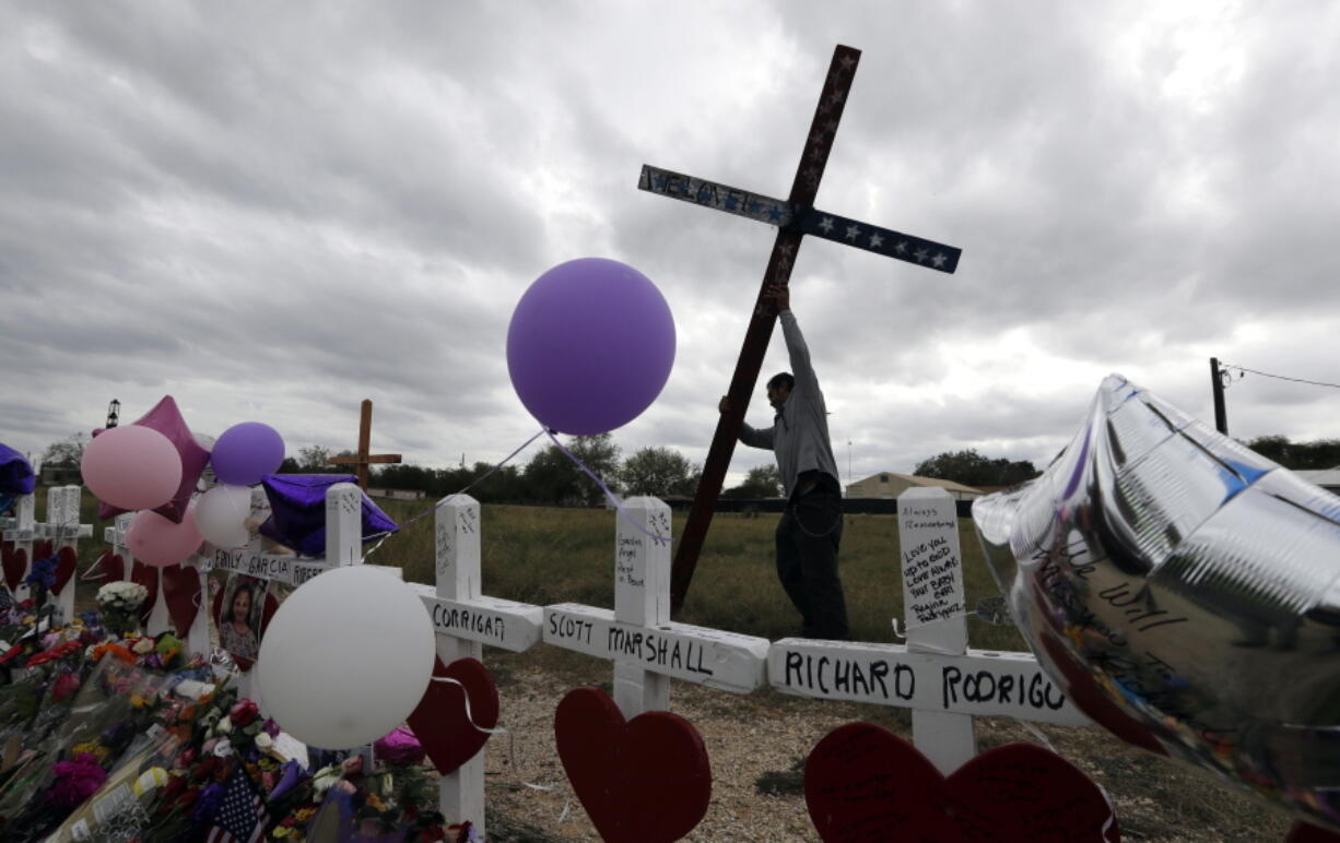 Miguel Zamora stands a cross for the victims of the Sutherland Springs First Baptist Church shooting at a makeshift memorial, Saturday in Sutherland Springs, Texas. A man opened fire inside the church in the small South Texas community on Sunday, killing more than two dozen. Zamora carried the cross for three days to reach the site.