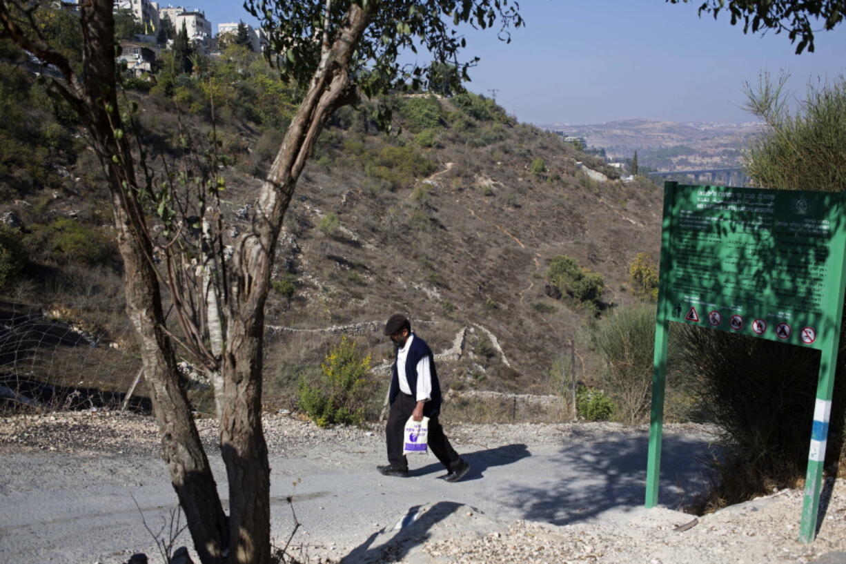 In this Wednesday, Oct. 25, 2017 photo, a man climbs up the hill in Lifta, on the western edge of Jerusalem. Lifta, a Palestinian village abandoned during the 1948 Arab-Israeli war, is at risk of demolition to make way for a luxury development. Some Israeli and Palestinian activists and are waging a legal battle to prevent bulldozers from destroying what’s left of the ruins and preserve them as an historic site.