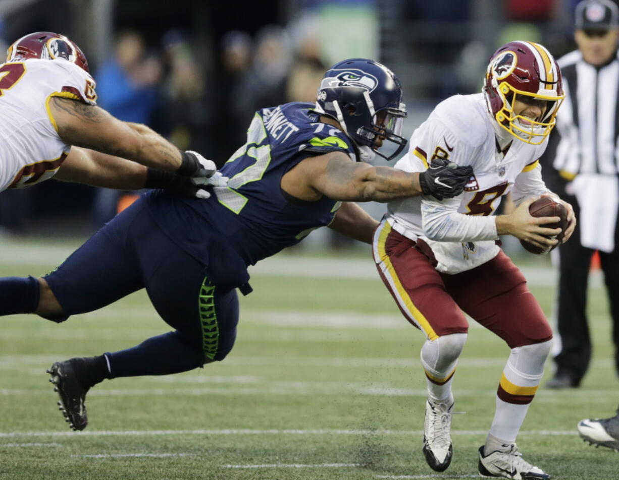 Washington Redskins quarterback Kirk Cousins, right, scrambles away from a tackle attempt by Seattle Seahawks defensive end Michael Bennett, left, in the second half of an NFL football game, Sunday, Nov. 5, 2017, in Seattle.