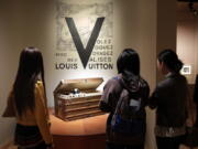 Visitors view a 1906 trunk, displayed as part of the “Volez, Voguez, Voyagez,” Louis Vuitton exhibit in the former American Stock Exchange building, in New York financial district. The luxury French brand was founded in the mid-19th century.