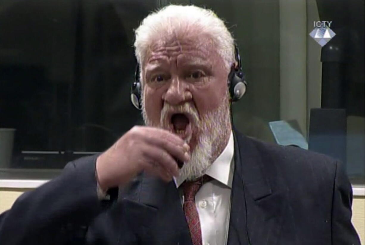 Slobodan Praljak brings a bottle to his lips, during a Yugoslav War Crimes Tribunal in The Hague, Netherlands. Praljak yelled, “I am not a war criminal!” and appeared to drink from a small bottle, seconds after judges reconfirmed his 20-year prison sentence for involvement in a campaign to drive Muslims out of a would-be Bosnian Croat ministate in Bosnia in the early 1990s.