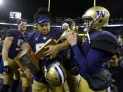 Washington quarterback Jake Browning, right, and defensive lineman Vita Vea, center, hold the Apple Cup trophy after Washington defeated Washington State 41-14 in an NCAA college football game, Saturday, Nov. 25, 2017, in Seattle. (AP Photo/Ted S.