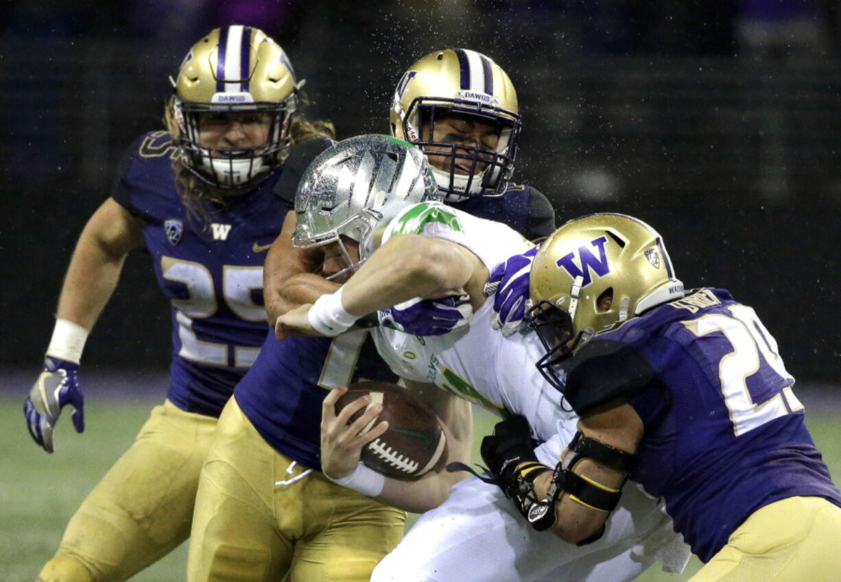 Oregon quarterback Braxton Burmeister is tackled by Washington linebackers Connor O’Brien, right, and Brandon Wellington, upper center. No. 9 Washington brings the best defense in the country into Friday’s matchup at Stanford. Ted S.