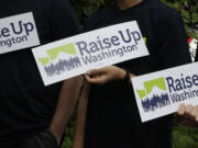 Supporters of raising the state minimum wage hold signs at a news conference, in 2016 in Olympia. Initiative 1433, approved by votes, incrementally increases the state's rate over the next four years to $13.50 an hour and to provide paid sick leave to employees who don't currently have it.