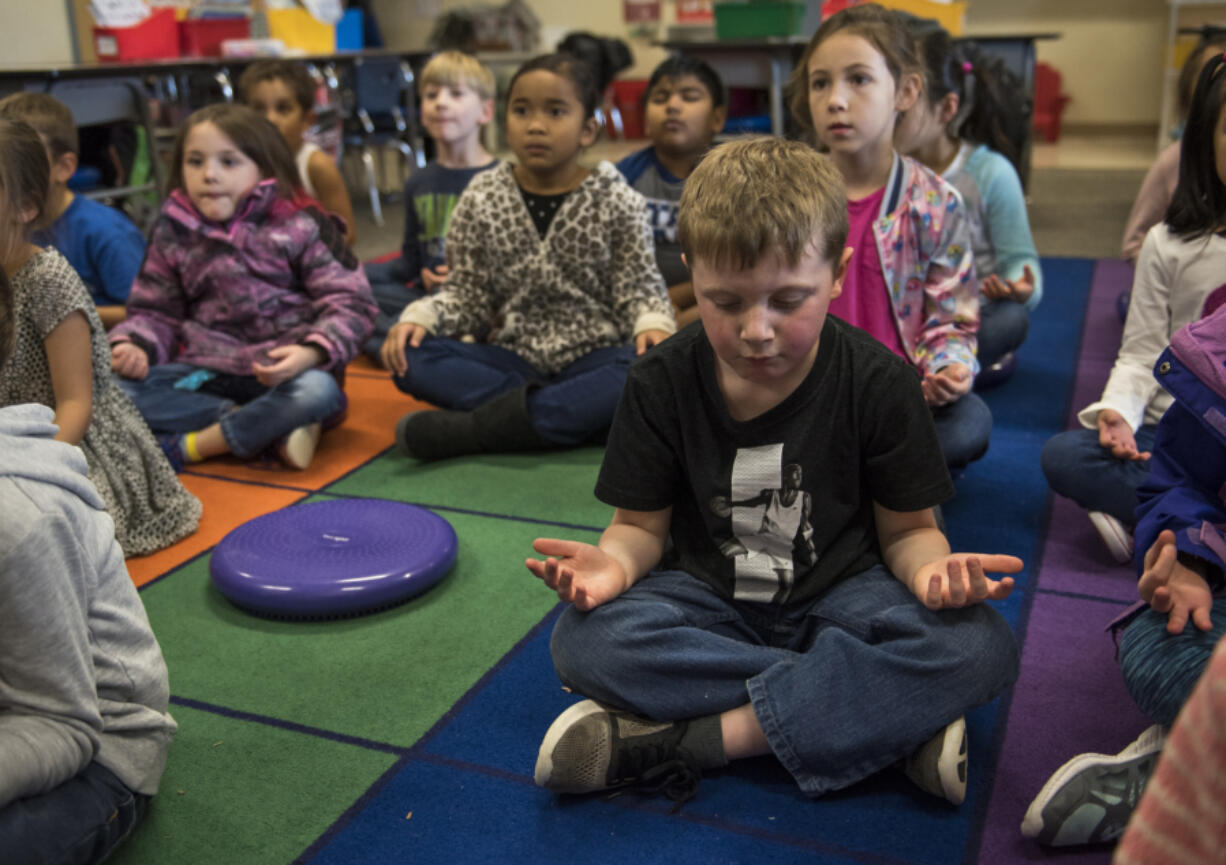 Carter Griffin closes his eyes during a mindfulness exercise after recess in Katrina Munro’s first-grade classroom at Illahee Elementary School earlier this month. Evergreen Public Schools classrooms are incorporating mindful meditation into their day-to-day activities. The goal is to get students conscious of their thinking and behavior, calm and focused, and less stressed in the classroom.