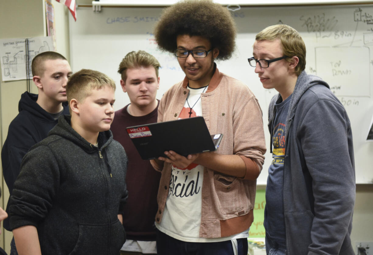 From left, Heritage High School students Seth Hastings, Landon Sanders, Daniel Adams, Terrence Lewis and Charles Chandler look at Lewis’ computer while designing a sound booth for their after-school game design team, the Heritage Lakoda Wolves.