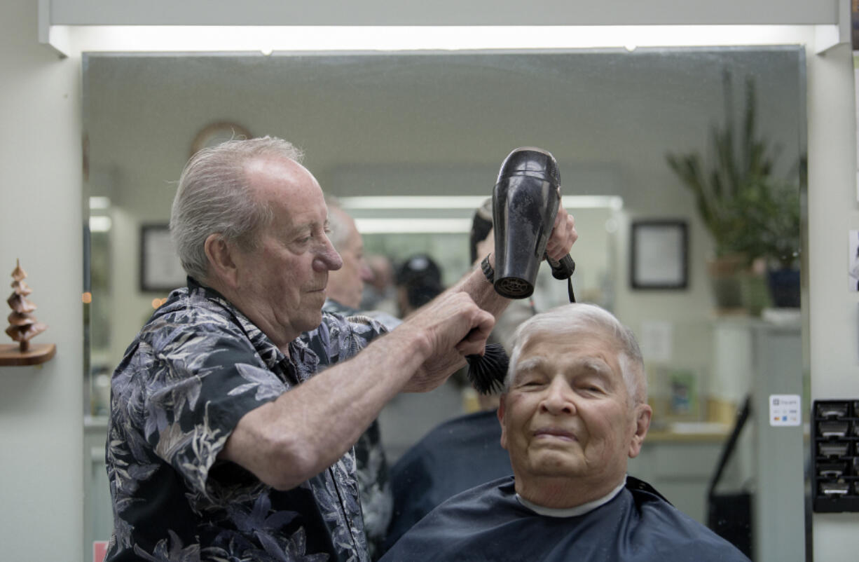 Bob Lutz, owner of Arlo’s Barber Shop, keeps longtime customer Ken Powell of Vancouver looking sharp with a quick haircut on Dec. 6. Lutz has been cutting hair for nearly 60 years.