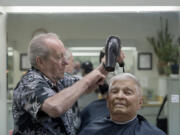 Bob Lutz, owner of Arlo’s Barber Shop, keeps longtime customer Ken Powell of Vancouver looking sharp with a quick haircut on Dec. 6. Lutz has been cutting hair for nearly 60 years.