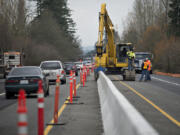 Motorists traveling north on state Highway 503, left, are routed around construction crews as they install a traffic barrier Friday afternoon in Battle Ground. The city is in the midst of its Congestion Relief Project at the intersection of highways 502 and 503, which sees around 50,000 drivers on an average weekday.