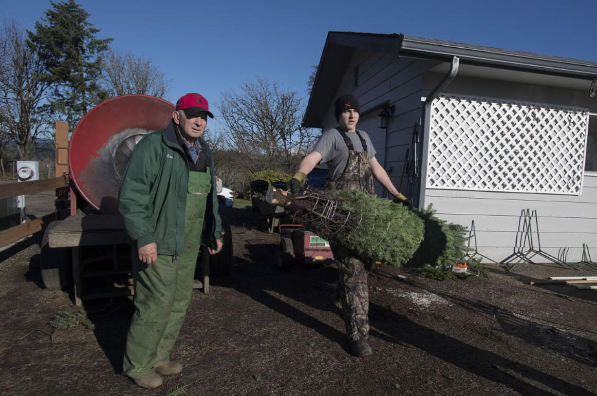 Bruce Wiseman, left, and neighbor Sean Morris help a customer with their tree at The Tree Wisemans in Ridgefield.