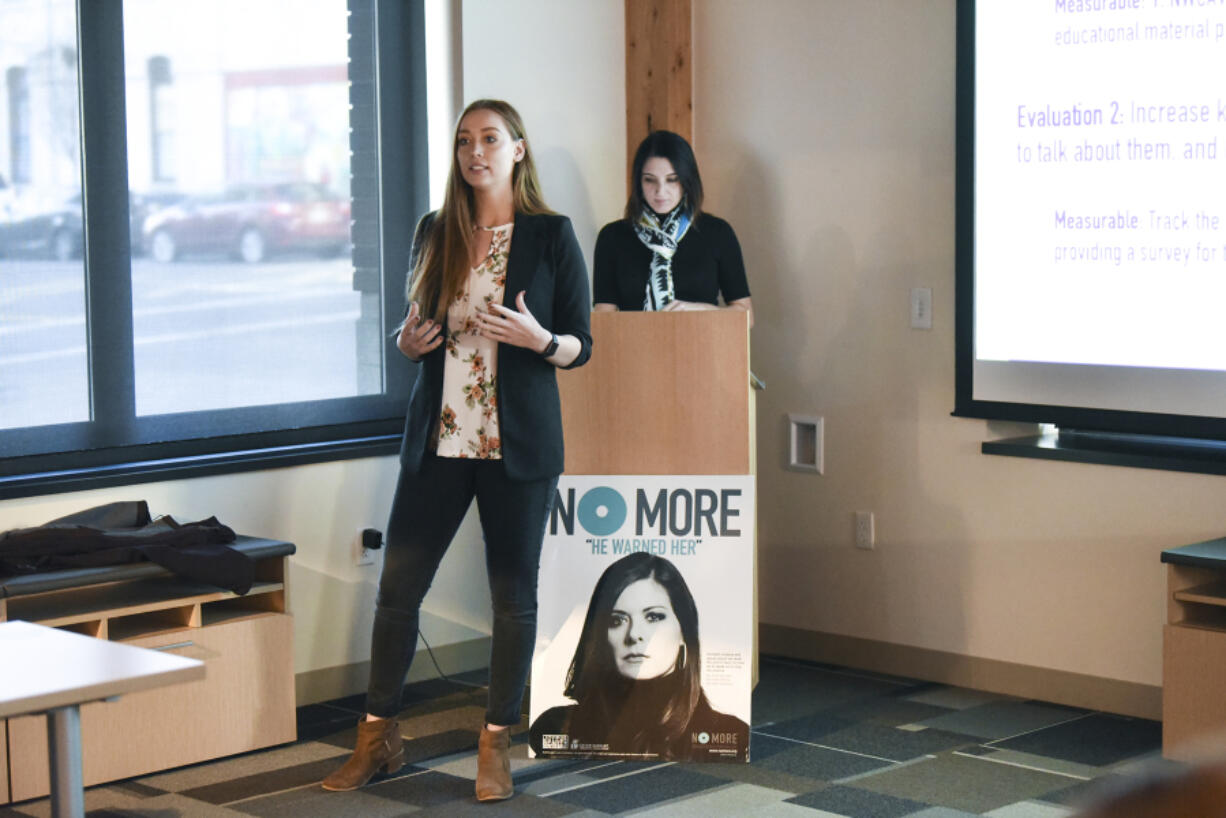 WSU Vancouver student Kelsie Reef, left, presents her team’s campaign to a group of judges and WSU Vancouver students Tuesday during the Washington Says No More campaign presentations, while her teammate Melanie Shelton prepares at the lectern behind her at Pacific Continental Bank in Vancouver.