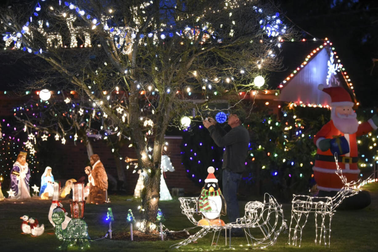 Rick Amies fixes a string of lights in the front yard of his Hazel Dell home, which is decorated with various Christmas decorations and lights, continuing a family tradition started by his parents in the Lincoln neighborhood.