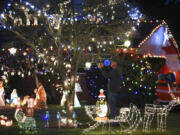 Rick Amies fixes a string of lights in the front yard of his Hazel Dell home, which is decorated with various Christmas decorations and lights, continuing a family tradition started by his parents in the Lincoln neighborhood.