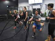 Jessica Denise, from left, Molly Maher and Jonathan Beckstead listen to directions from instructor Kathrine Kofoed at Burntown. The new high-intensity fitness studio opened in east Vancouver last month.