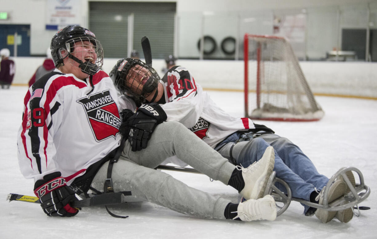 Connor Foppe, 16, left, laughs as his hockey teammate, Randy Yeakley, tries to pull Foppe upright after his sled tipped over during practice at Mountain View Ice Arena, Wednesday December 6, 2017. Foppe suffered a stroke in April and has been regaining mobility on the right side of his body. His teammates joined him on sleds to practice with members of the Portland Winterhawks sled team and Paralympic sled hockey gold medalist Josh Sweeney.