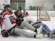 Connor Foppe, 16, left, laughs as his hockey teammate, Randy Yeakley, tries to pull Foppe upright after his sled tipped over during practice at Mountain View Ice Arena, Wednesday December 6, 2017. Foppe suffered a stroke in April and has been regaining mobility on the right side of his body. His teammates joined him on sleds to practice with members of the Portland Winterhawks sled team and Paralympic sled hockey gold medalist Josh Sweeney.