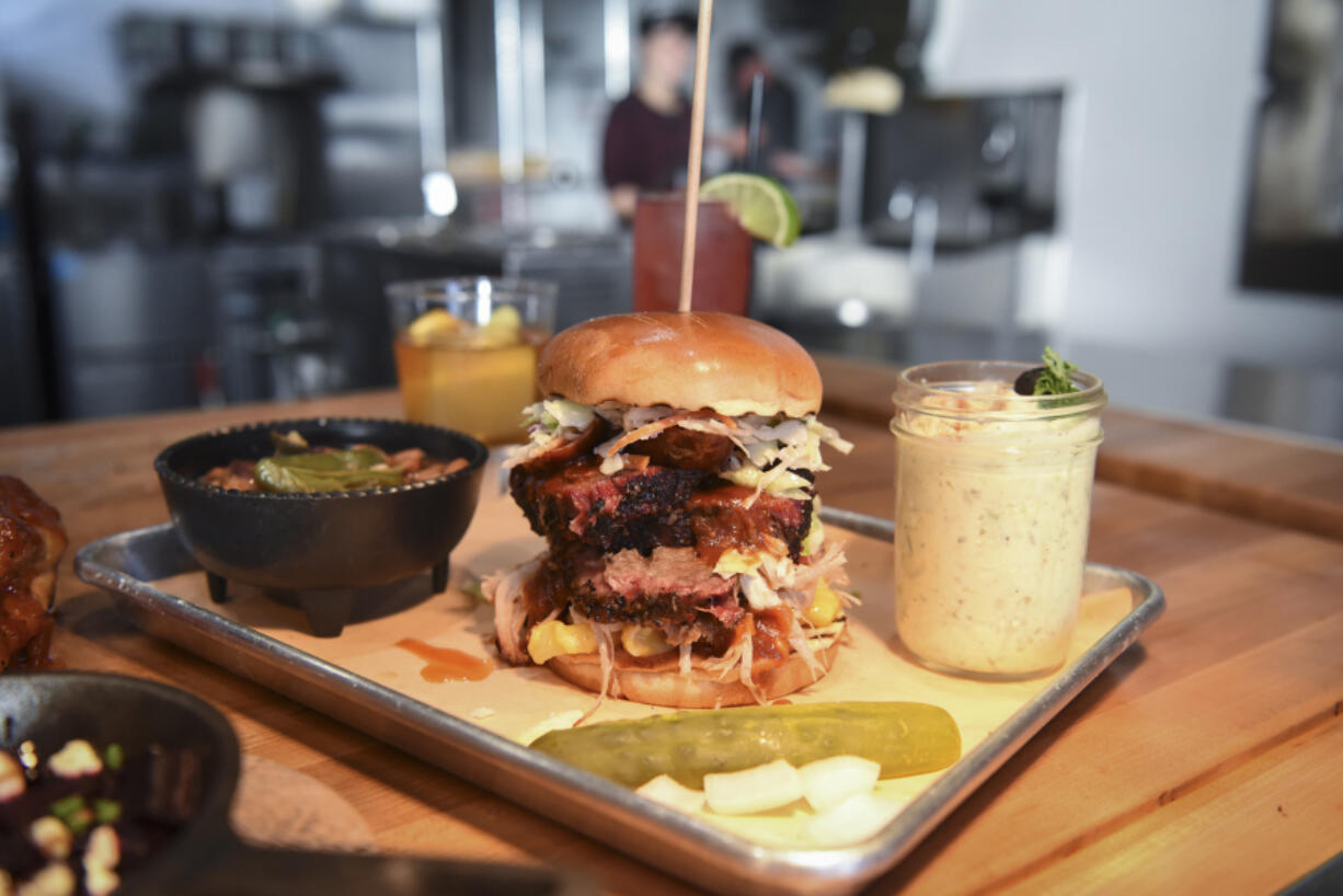 Jalapeño pinto beans, left, are shown with the “The Fatty” sandwich (brisket, pulled pork and sausage) and potato salad at The Smokin’ Oak in downtown Vancouver.