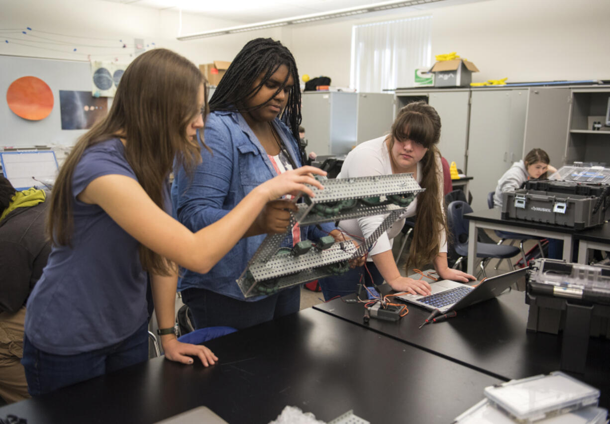 Vancouver iTech Preparatory freshman Emily Neumann, from left, junior Brooklyn Terry and freshman Elizabeth Zavala test out the wheels on their prototype during a robotics class at the school on Monday. The school boasts a curriculum preparing students for college and careers in science and engineering fields. But with a predominantly white student body, experts worry iTech and similar magnet schools are exacerbating barriers for students of color.