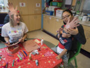 Renee Dieffenderfer of Creations for Cures, left, looks on as patient Sergio Cano Marquez, 3, of Portland tries on a reindeer headband with the help of his mom, Laura Marquez, on Dec. 18 at Doernbecher Children’s Hospital. Dieffenderfer turned to art for an escape while undergoing chemotherapy for Hodgkin’s lymphoma. For the last year, she has brought art projects to kids at the hospital.