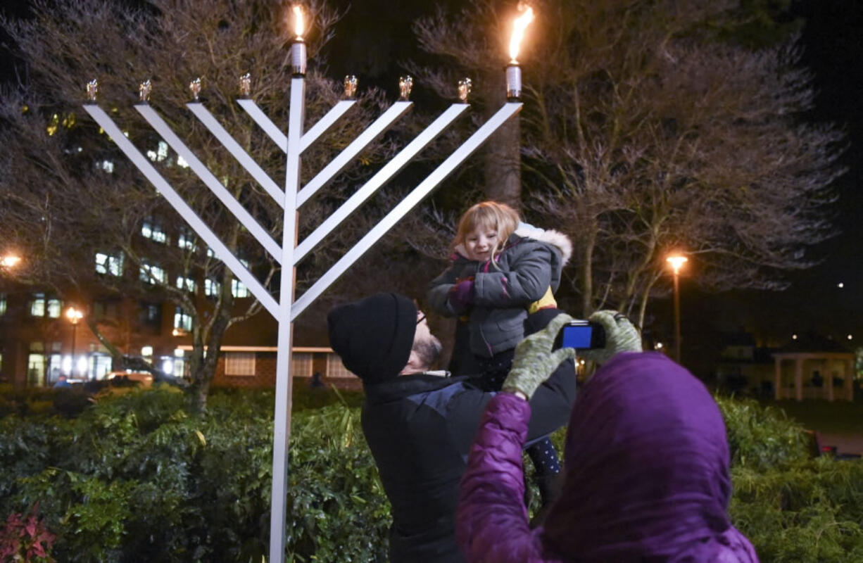 Ephraim Barstad holds up his daughter, Selah Barstad, 3, for a photo Tuesday at the annual menorah lighting at Esther Short Park in downtown Vancouver.