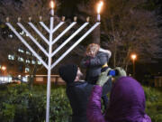 Ephraim Barstad holds up his daughter, Selah Barstad, 3, for a photo Tuesday at the annual menorah lighting at Esther Short Park in downtown Vancouver.