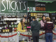 Budtender Sarah Rosdahl, left, and Kayzla Worlitz, an assistant manager at Sticky’s Pot Shop, help customers pick out products on Wednesday. The shop remains open, despite a county ban, while the law is contested in the courts.