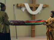 Marcella Leonard, left, and Marianna Leonard fold the African-American flag at the beginning of the Kwanzaa Celebration at the New Directions Community Church in Vancouver on Saturday.