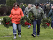 Carol, left, and John Shields carry wreaths to place on military graves at Evergreen Memorial Gardens as part of the Wreaths Across America activities Saturday.