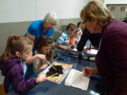 Hazel Dell: Washington State University Master Gardeners Genda McCune, left, and Linda Ricciardi look on as first-grade students from Hazel Dell Elementary School explore compost and find red wiggler worms and other soil life.