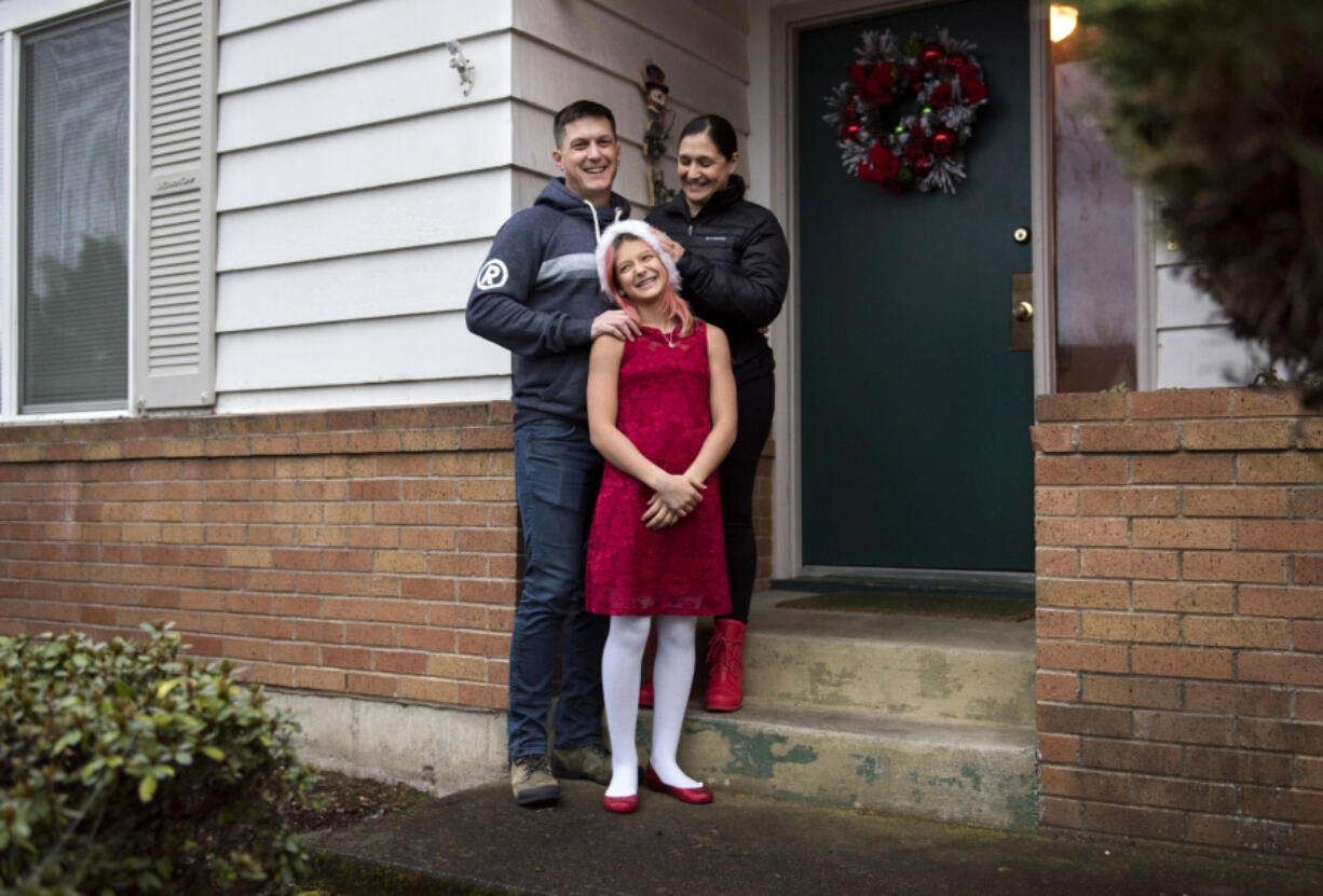 Will Mantz, left, and his wife, Jannea, right, stand outside their house with their daughter Ari. They rent their home and are hopeful the housing market will balance out soon so they can buy.