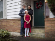 Will Mantz, left, and his wife, Jannea, right, stand outside their house with their daughter Ari. They rent their home and are hopeful the housing market will balance out soon so they can buy.