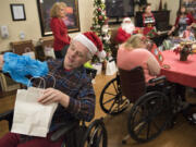 Jerry Gensler, left, a resident of Prestige Care and Rehabilitation in Camas, on Tuesday opens a gift delivered through Home Instead Senior Care’s Be a Santa to a Senior drive.