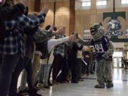 Dressed as Terry the T-Wolf, Heritage High School senior Robbie Meadors high-fives a long line of fellow students on Tuesday afternoon at Heritage High School. The school estimates that 150 students lined up to try to break the world record of 128 high-fives by a school mascot in one minute. Most saluted Terry the T-Wolf twice.