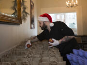 Brandon Dickover places apples in bags to be donated to the needy on Christmas Day at Bleu Door Bakery on Monday.