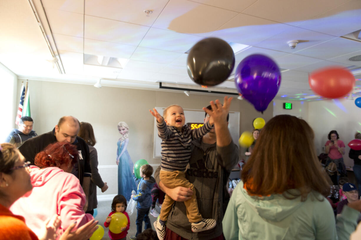 Reed Rissler, 2, swats at celebratory balloons with his father, Ryan Rissler of Camas, during the Camas Public Library’s Noon Year’s Eve dance party Saturday.