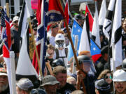 FILE - In this Saturday, Aug. 12, 2017, file photo, white nationalist demonstrators walk into the entrance of Lee Park surrounded by counter demonstrators in Charlottesville, Va.  A former federal prosecutor says the law enforcement response to a white nationalist rally this summer in Charlottesville that erupted in violence was a series of failures. The findings of former U.S. Attorney Tim Heaphy's monthslong investigation were unveiled Friday, Dec. 1. City officials asked him to conduct the review after facing scathing criticism over the Aug.