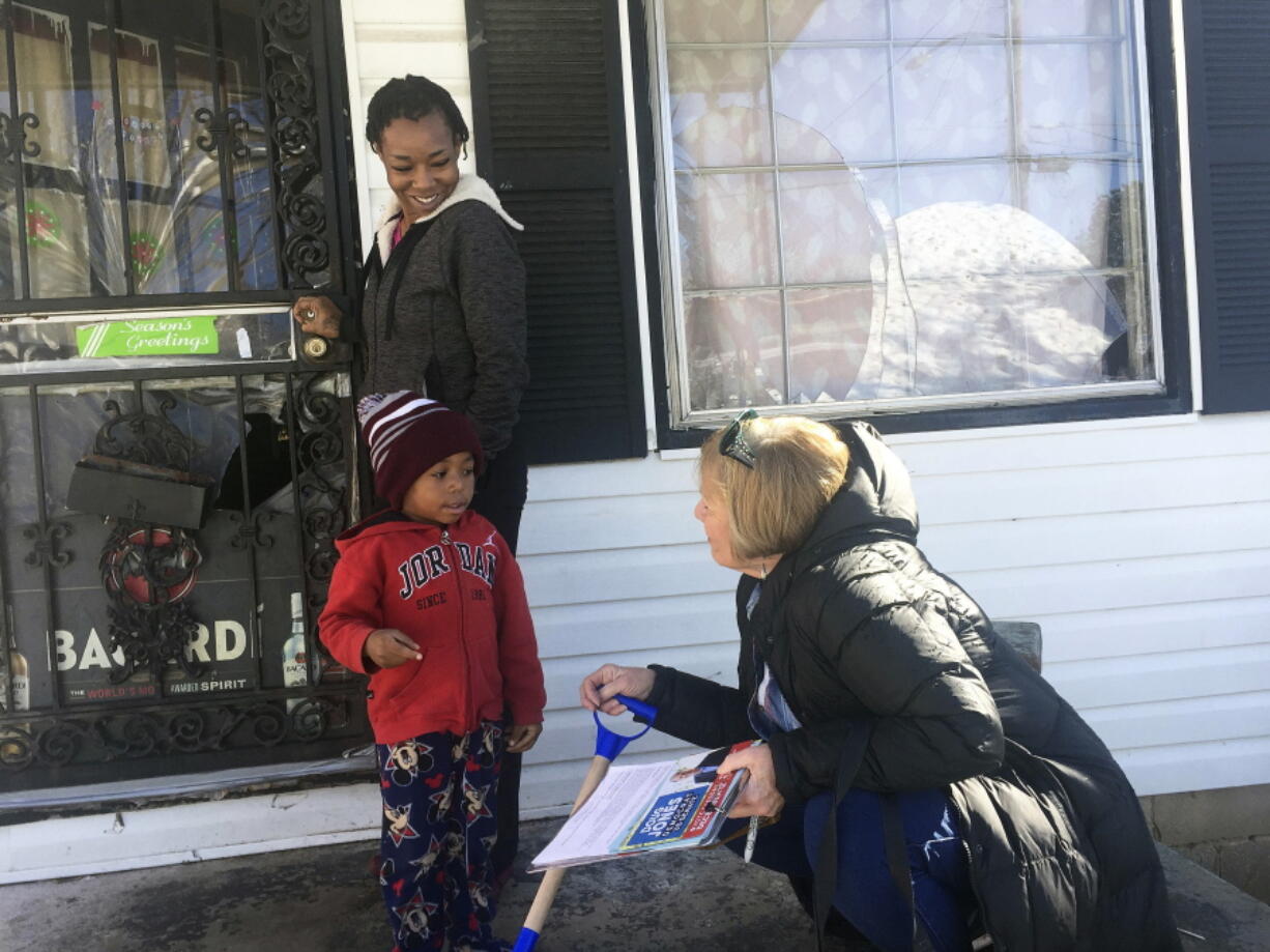 Doug Jones’ campaign volunteer Dana Ellis, right, talks to Ebonique Jiles, top left, and her son, Saturday, Dec. 9, 2017, in Birmingham, Ala., about voting on Tuesday’s senatorial election, The Jones campaign is targeting African-Americans and moderate Republicans in particular as they fight to energize a coalition to defeat Republican Roy Moore.