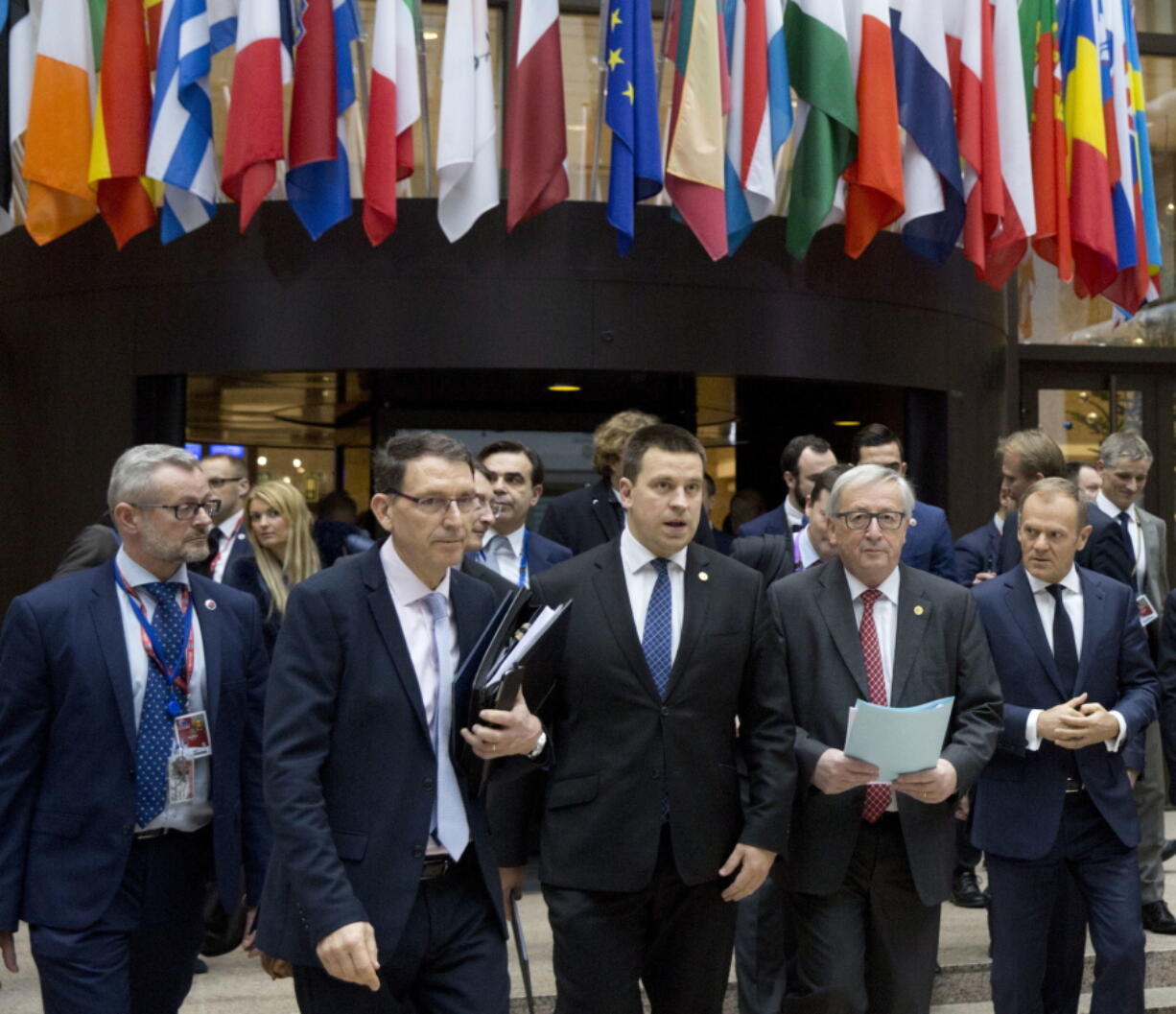 European Council President Donald Tusk, right, and European Commission President Jean-Claude Juncker, second right, pass through the press room on their way to a media conference at an EU summit in Brussels on Friday, Dec. 15, 2017. European Union leaders were set Friday to authorize a new phase in Brexit talks as time runs short to clinch an agreement on future relations and trade with Britain before it leaves the bloc in March 2019.