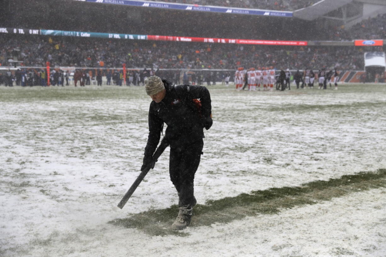 A worker clears snow from field lines at Soldier Field during an NFL football game between the Chicago Bears and Cleveland Browns in Chicago, Sunday, Dec. 24, 2017.