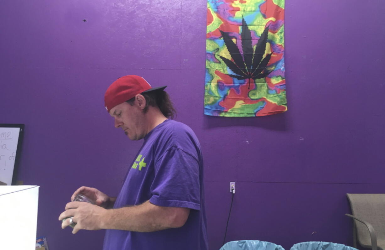 In this Tuesday, Oct. 3, 2017, photo, Thomas Grier works as a “bud tender” at Canna Can Help Inc., a medical marijuana dispensary in Goshen, Calif. Labor unions are vying to represent California cannabis workers when a new law takes effect in 2018 legalizing the sales of recreational marijuana.