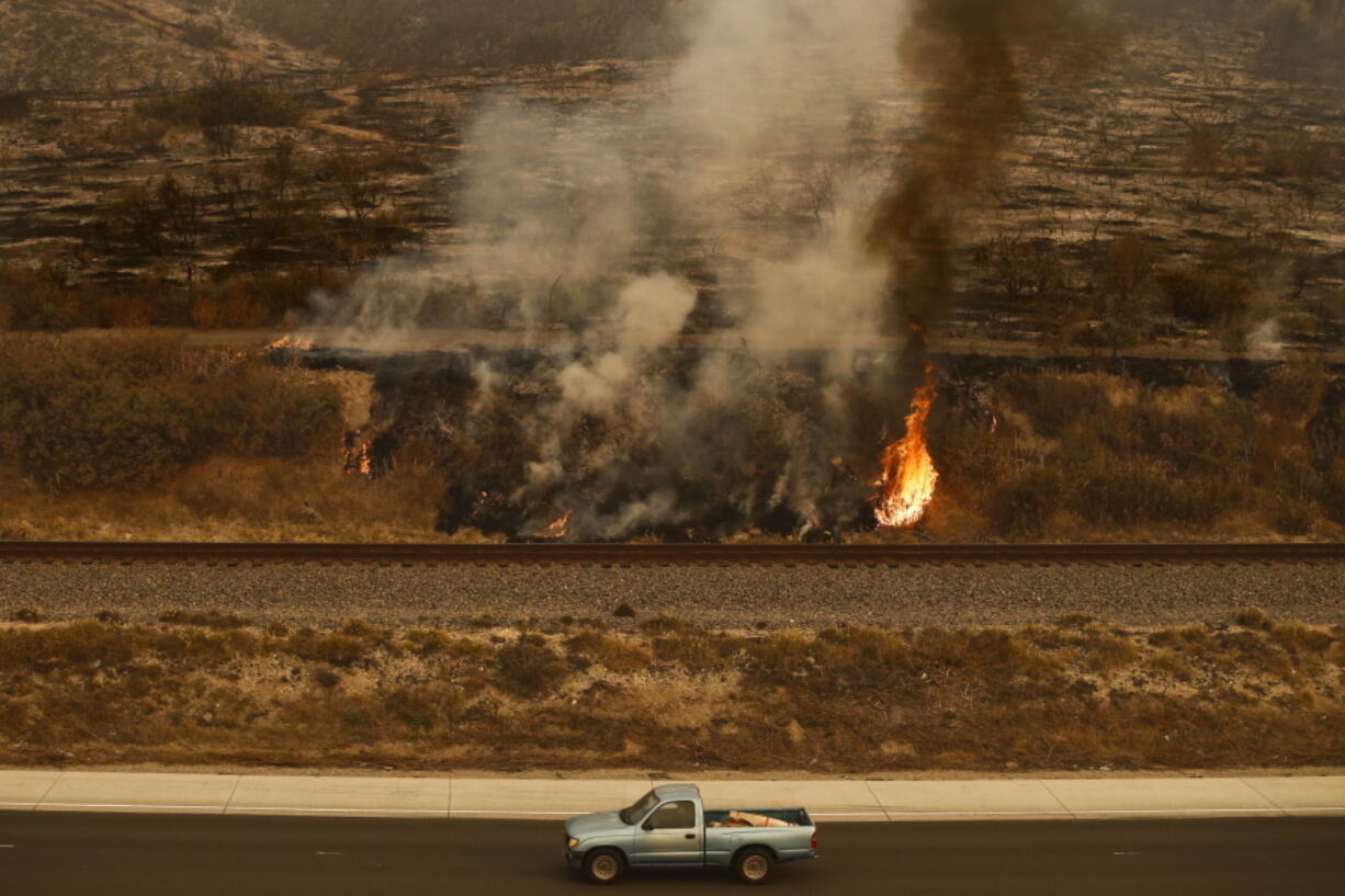 A pickup truck passes a wildfire burning along the 101 Freeway in Ventura, Calif., Thursday, Dec. 7, 2017. The wind-swept blazes have forced tens of thousands of evacuations and destroyed dozens of homes. (AP Photo/Jae C.