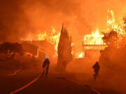 Ventura County Fire Department firefighters work to put out a blaze burning homes early Tuesday in Ventura, Calif. Authorities said the blaze broke out Monday and grew wildly in the hours that followed, consuming vegetation that hasn’t burned in decades.